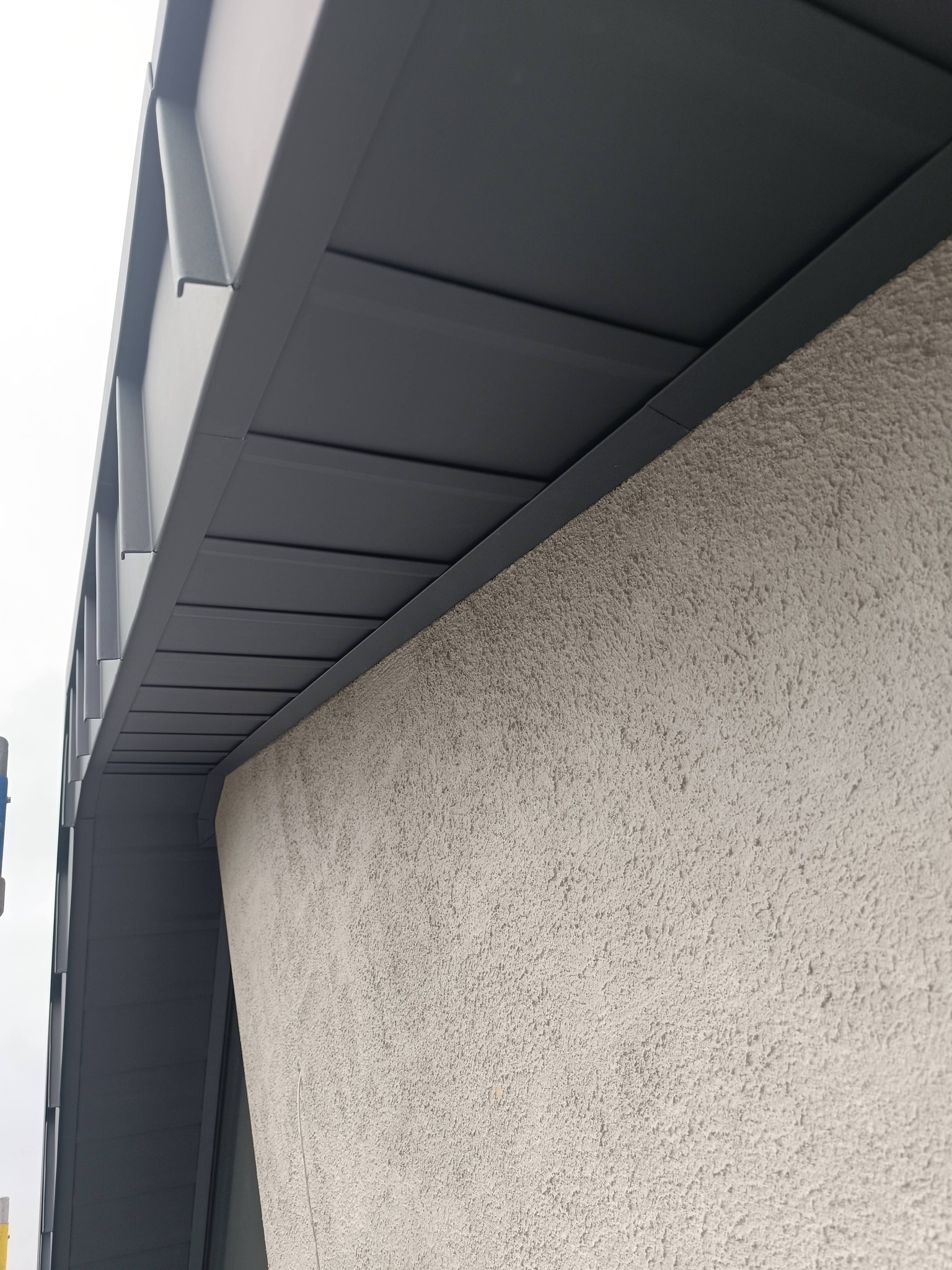 Close-up detail of architectural metal soffit meeting concrete