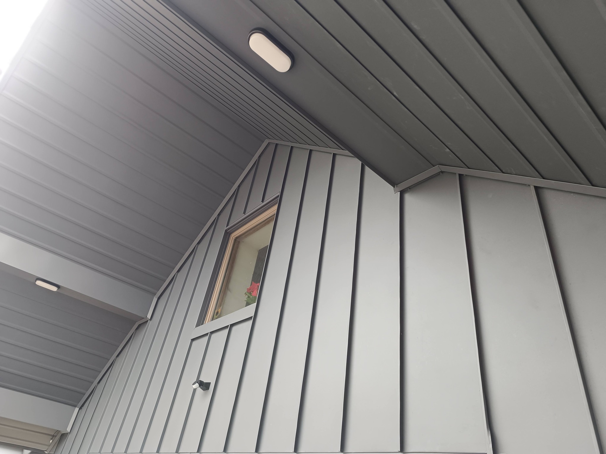 Upward view of precise white vertical metal cladding meeting soffit